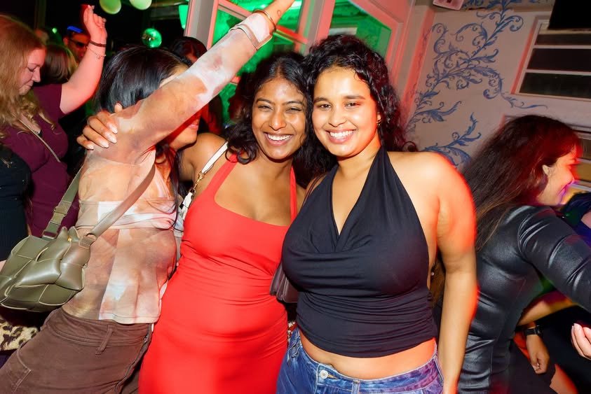 Two friends smiling on the crowded Back to the 2000s Auckland dancefloor